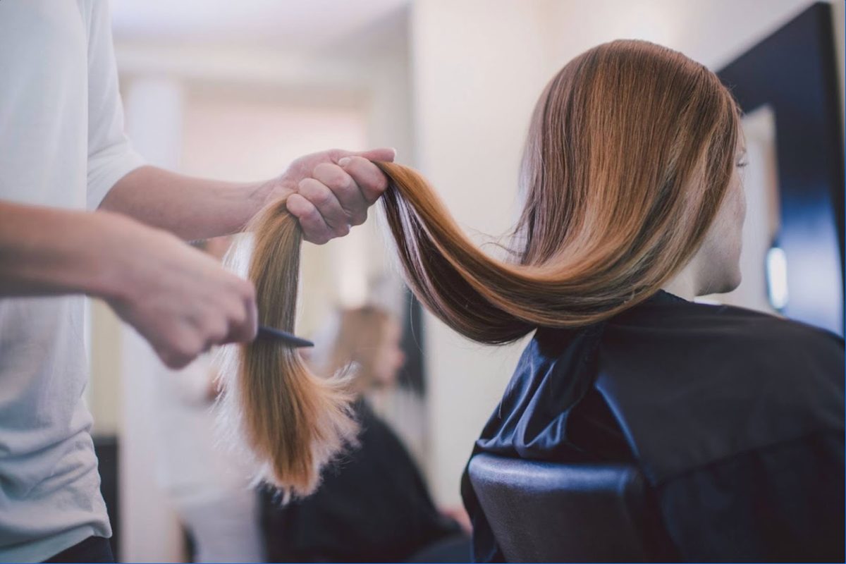 Stylist mid-service with both hands busy while the salon phone rings